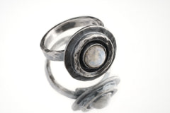 Blue Moonstone Ring shown on white background with raised textured silver face and adjustable open band.