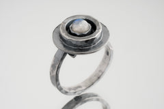 Blue Moonstone Ring shown from the side with oval cabochon, raised bezel setting, and textured silver band.