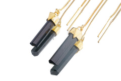 Close-up of gold-plated Tourmaline earrings showing dark crystal drops, fine hook fittings, and warm gold finish.