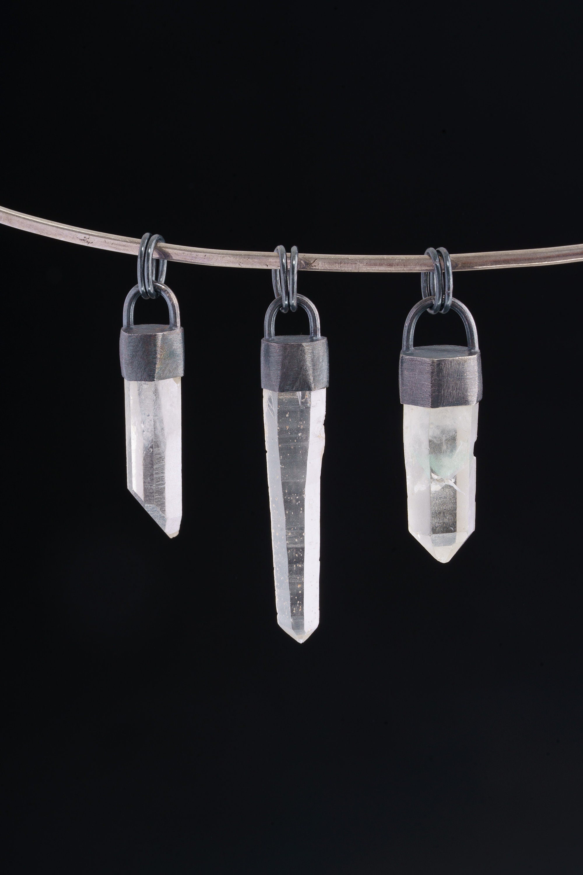 Three hand fossicked Australian Clear Quartz point pendants in oxidized 925 sterling silver, shown on black with coil bails.