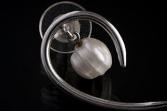 Close view of handmade Pearl earrings showing curved sterling silver swirl design and polished reflective finish.