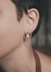 Handmade 925 sterling silver Pearl swirl earrings shown worn on the ear, with natural Pearl and curved silver drop design.