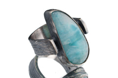 Larimar rock-hammered ring in oxidized 925 sterling silver with open-back bezel and soft ocean-blue stone.