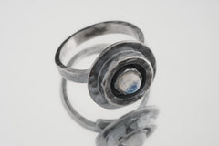 Blue Moonstone Ring shown on white background with hammered oxidized silver and pale lunar gemstone centre.