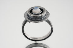 Blue Moonstone Ring shown on white background with oxidized sterling silver setting and oval blue-white cabochon.