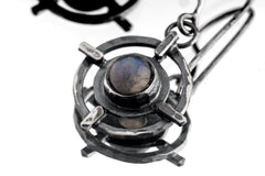 Close-up of Labradorite Circle Cross earring showing bezel-set stone, hammered silver texture, and layered talisman form.