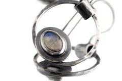 Close-up of Labradorite Cat Eye earring showing hammered silver texture, circular frame, and blue-grey gemstone flash.