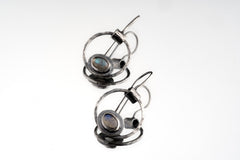 Old World Labradorite Cat Eye earrings in hammered 925 sterling silver shown worn on the ear with circular dangle form.