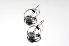 Old World Labradorite Cat Eye earrings in hammered 925 sterling silver shown worn on the ear with circular dangle form.