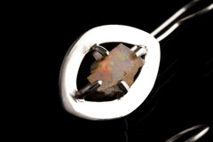 Close-up of Australian White Opal earring showing polished sterling silver halo setting and natural play of colour.