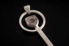 Close-up of Clear Quartz spoon pendant showing hammer-textured sterling silver and light-catching crystal setting.