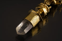 Close-up of Himalayan Clear Quartz crystal suspended beneath a sand-textured brass Ganesha talisman pendant.