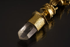 Close-up of Himalayan Clear Quartz crystal suspended beneath a sand-textured brass Ganesha talisman pendant.
