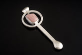 Rhodochrosite sterling silver hammered spoon pendant shown on dark background with pink stone and sculptural spoon form.