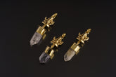 Meditating Ganesha Clear Quartz talisman pendant shown on black background with golden brass figure and crystal point.