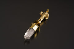 Standing Ganesha Clear Quartz pendant shown on a dark background with warm brass setting and clear crystal point.