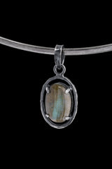 Horizontal Madagascan Labradorite pendant on a black background, set in oxidized 925 sterling silver with claw prongs and hammered texture.