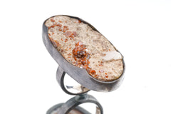 Side view of adjustable Garnet Calcite ring showing thick waved bezel, open-back setting, and shiny sterling silver band.