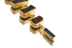 Close-up of gold-plated Tourmaline pendant showing linked gemstone sections, sand-textured settings, and mixed crystal colours.