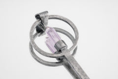 Close-up of Amethyst Generator spoon showing brushed sterling silver texture and pointed purple crystal setting.