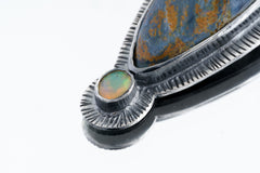 Close-up of Pietersite Opal pendant showing Ethiopian Opal accent and textured sterling silver sunburst detail.