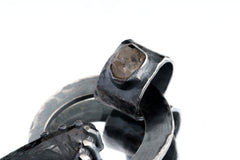 Close view of Black Rutile Quartz set onto the bail of a raw Moonstone silver pendant.