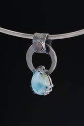 Larimar and Blue Moonstone pendant on black background with oxidized sterling silver ring and claw-set blue teardrop stone.