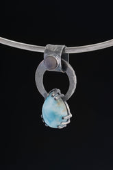 Larimar and Blue Moonstone pendant on black background with oxidized sterling silver ring and claw-set blue teardrop stone.