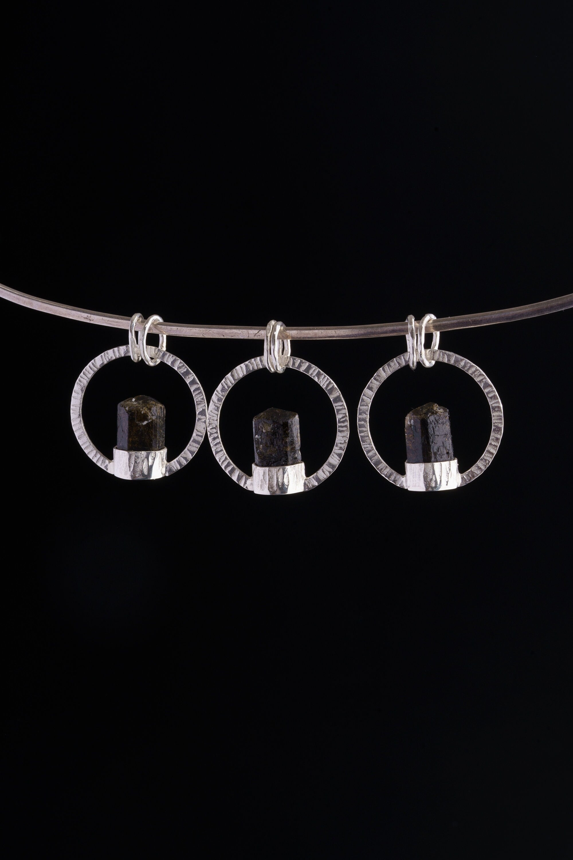 Himalayan Tourmaline halo pendant displayed on silver choker against black background.