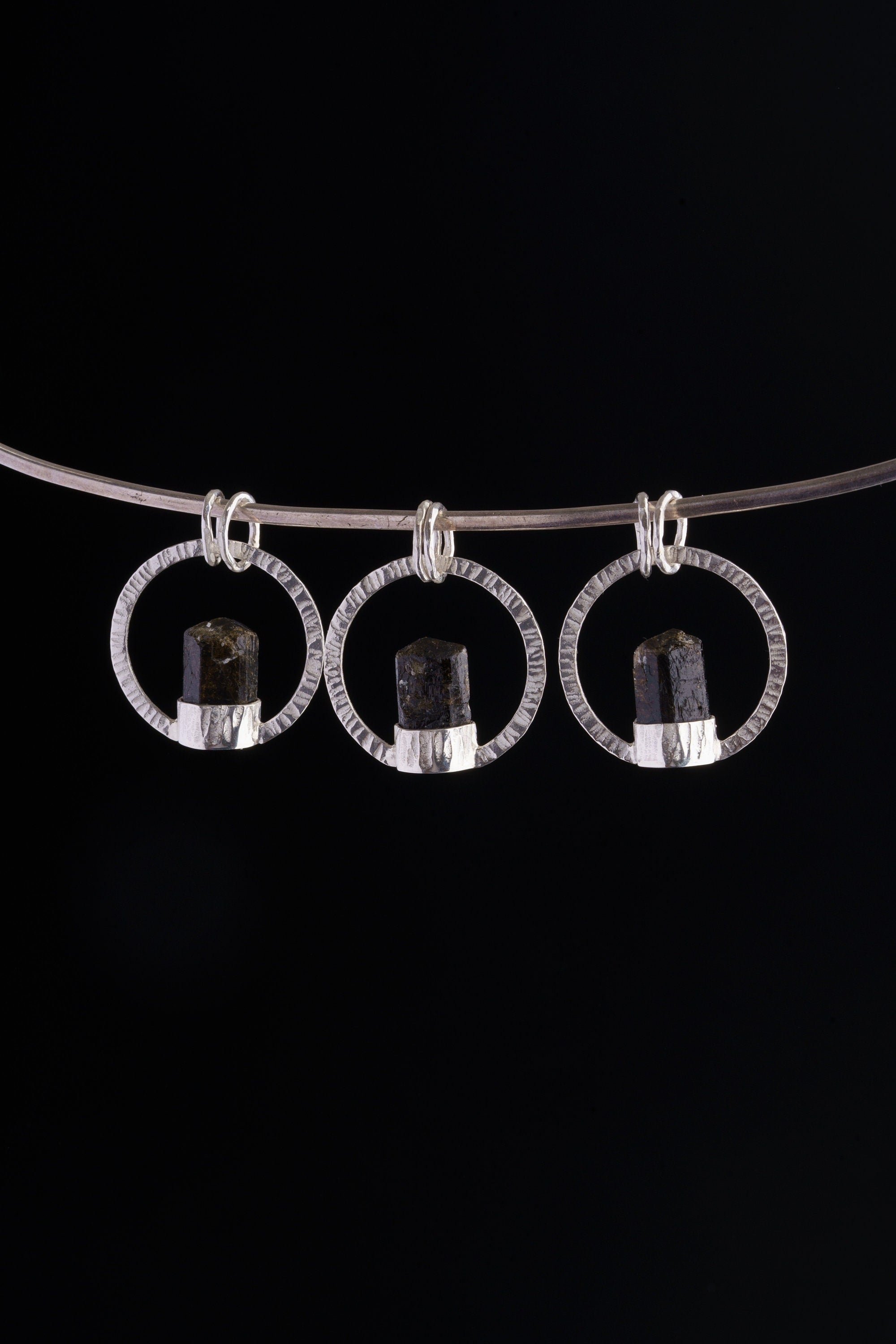 Himalayan Tourmaline halo pendant displayed on silver choker against black background.