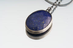 Close-up of circular faceted Lapis Lazuli in an oxidized sterling silver open-back bezel setting.