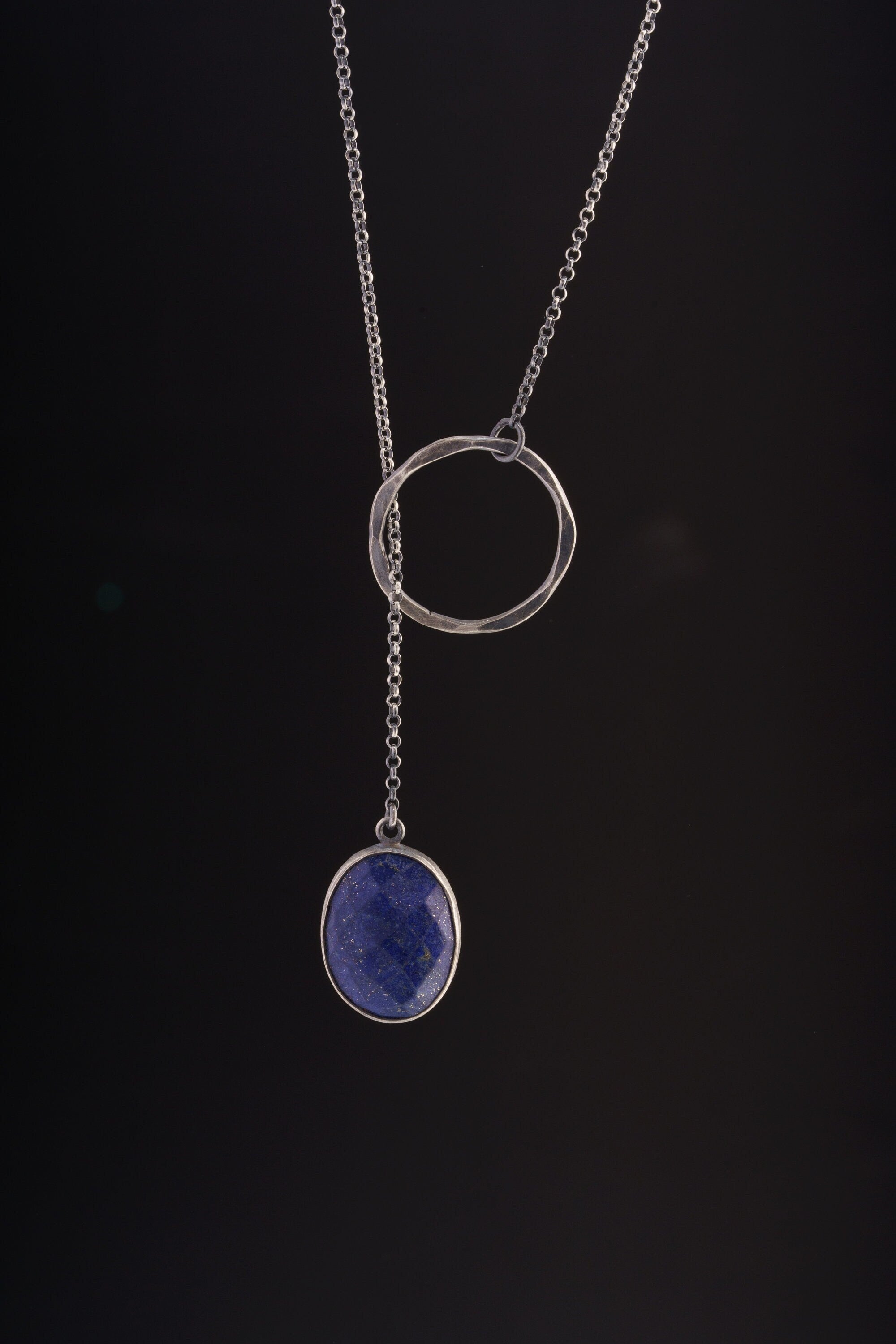 Faceted Lapis Lazuli adjustable lariat necklace shown on black background, with oxidized sterling silver ring closure and long chain.