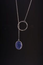 Faceted Lapis Lazuli adjustable lariat necklace shown on black background, with oxidized sterling silver ring closure and long chain.
