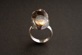 Ancient crystalized shell ring shown on dark background with adjustable sterling silver statement setting.