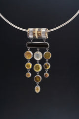 Carved Bone Tourmaline Amber Labradorite pendant shown on a black background with warm Amber and Rainbow Labradorite details.