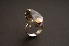 Crystalized shell statement ring shown on dark background with fossil texture and handmade silver setting.