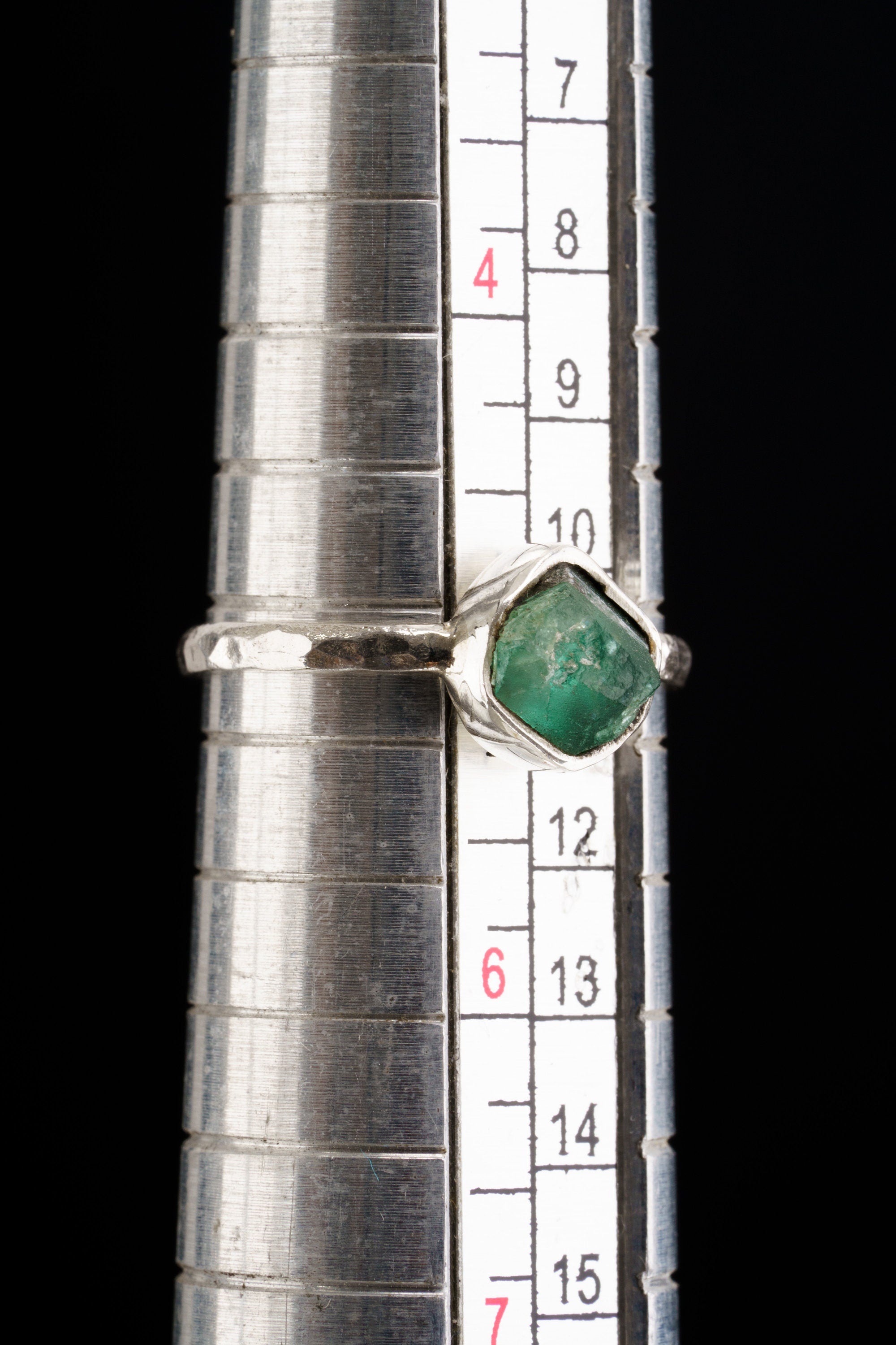 The mandrel image suggests the ring is approximately US size 5.5 to 6, but the exact size should be confirmed before publishing. The listing states Australian Raw Emerald and approx. 2 mm sterling silver band, so those details were prioritized. No more specific mine or locality was added.