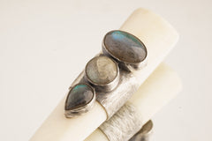 Close-up of antique bone tube pendant showing 925 sterling silver band with oval, round, and teardrop Labradorite stones.