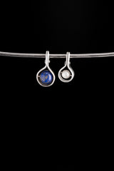 Two small sterling silver spinner pendants shown hanging on a chain, including Pearl and blue stone versions.