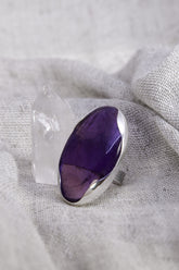 Oval Amethyst adjustable ring in high-shine 925 sterling silver shown on soft fabric with a polished purple gemstone.