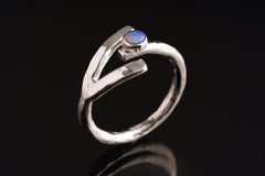 Dowsing Radiance Opal Ring shown on black background with adjustable sterling silver band and blue Opal focal stone.