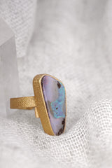 Side view of gold-plated Opal adjustable ring showing raised waved bezel, textured band, and cut-out support plate.