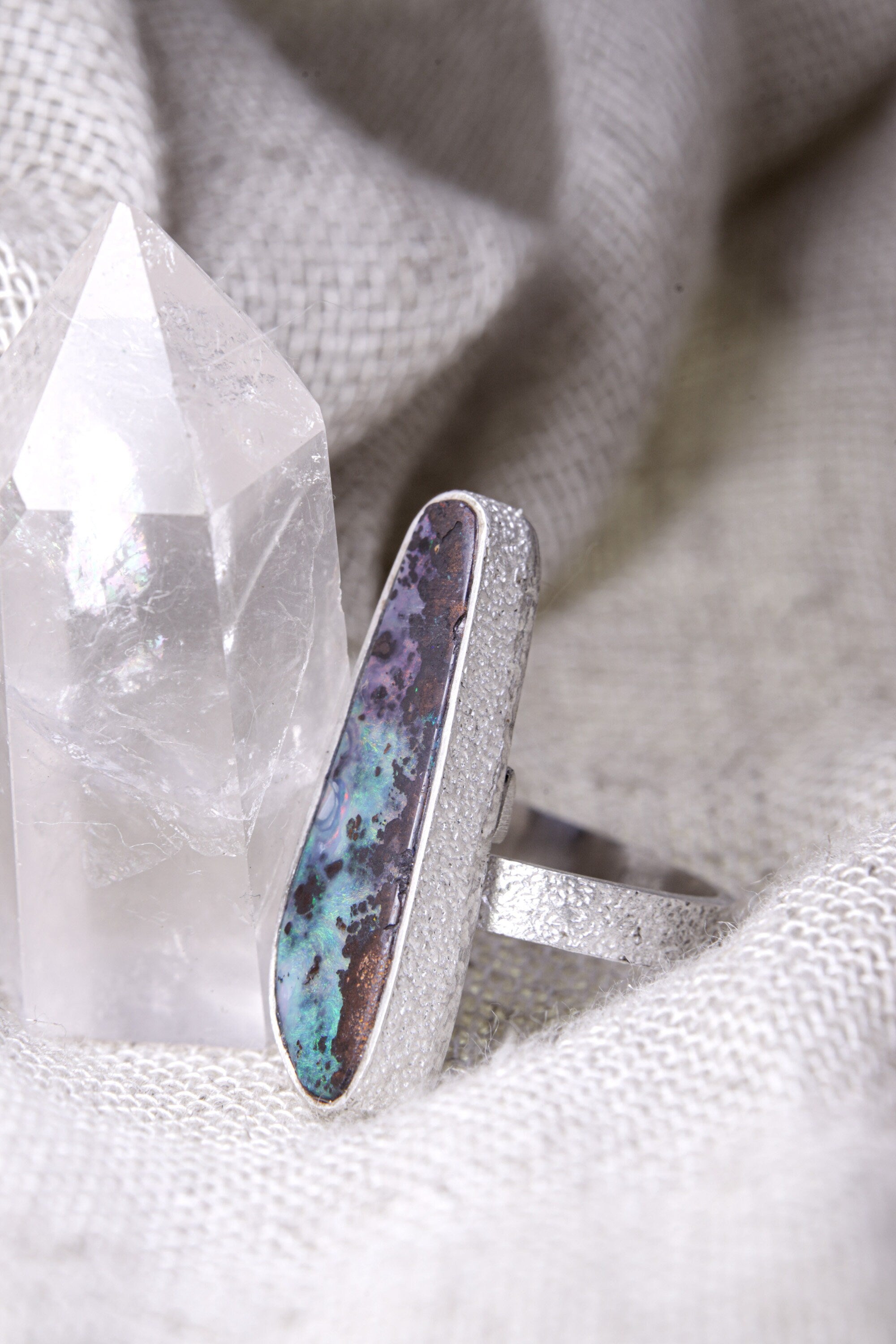 Side view of Opal adjustable ring showing the waved bezel, textured sterling silver band, and raised handmade setting.