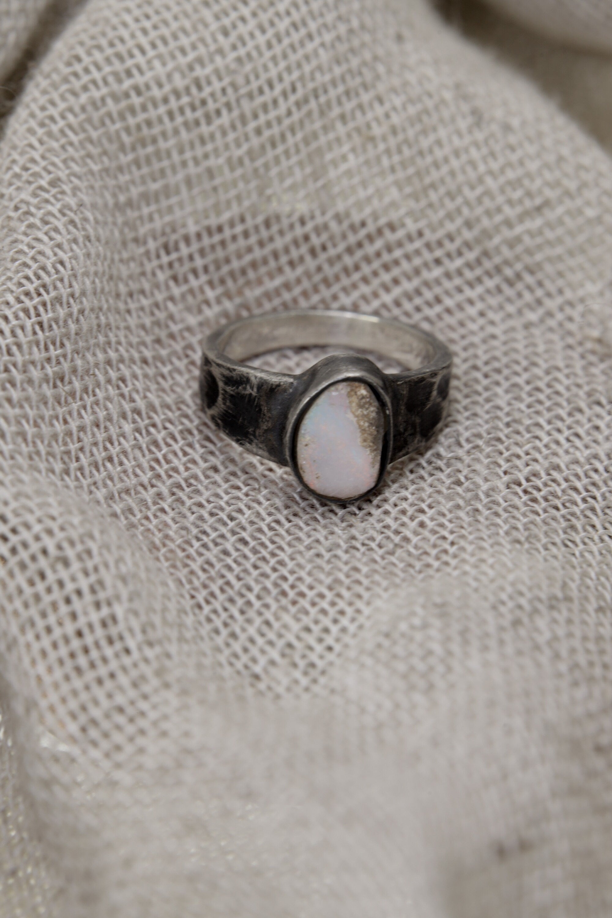 Lightning Ridge Gem Opal ring displayed on fabric, with lightly oxidized sterling silver setting and soft opal colour play.