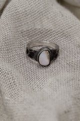 Lightning Ridge Gem Opal ring displayed on fabric, with lightly oxidized sterling silver setting and soft opal colour play.