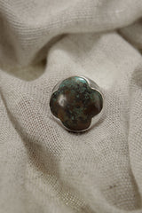 Himalayan Turquoise ring shown on soft fabric, with textured sterling silver band and earthy blue-green stone.
