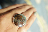 Himalayan Turquoise adjustable ring in high-shine 925 sterling silver shown worn on the hand with blue-green matrix stone.