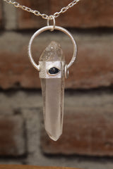 Australian Lemurian Quartz Sapphire Halo Pendant shown on brick background with sterling silver chain and vertical clear Quartz point.