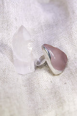 Triangular Rose Quartz ring shown on soft fabric, with waved bezel setting and polished sterling silver band.