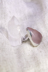 Triangular Rose Quartz ring shown on soft fabric, with waved bezel setting and polished sterling silver band.